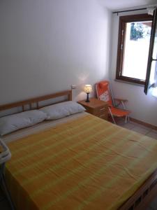 a bedroom with a bed and a chair and a window at Sardamare Casa Vacanze in Torre Dei Corsari