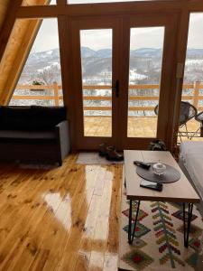 a living room with a table and large windows at MajdanskiKutak2 in Gornji Milanovac