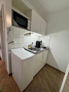 een kleine keuken met een spoelbak en een magnetron bij Studio Ohlendorf 3 Min zur A7 in Seevetal