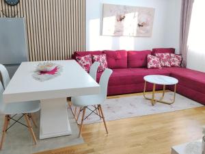 een woonkamer met een roze bank en een tafel bij GREEN HILL Lux Apartments in Soko Banja