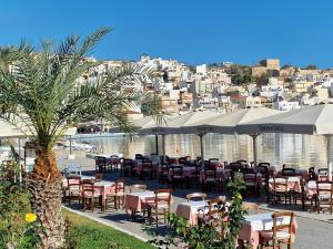 un ristorante con tavoli e ombrelloni di fronte all'acqua di Aggel's Infinity View Villa - private pool a Káto Episkopí