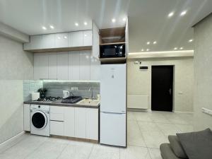 een keuken met witte kasten en een wasmachine en wastafel bij GSS - 3 Apartment in Tbilisi City