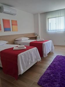 a bedroom with two beds with red and white sheets at Carambola CoLiving in Olinda