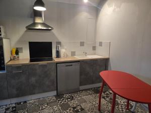 a kitchen with a red chair and a sink at L'orée des 3 Rivières in Is-sur-Tille