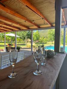 drei Weingläser auf einem Holztisch in der Unterkunft Cabañas el rincón de Colbún in Colbún