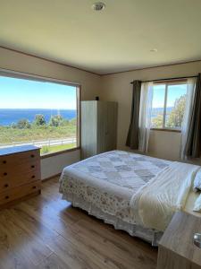 a bedroom with a bed and a large window at Casa con acceso directo al lago y hermosas vistas in Puerto Varas