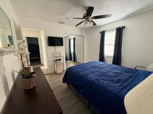 een slaapkamer met een blauw bed en een plafondventilator bij Dos alcobas, entrada independiente in Kissimmee