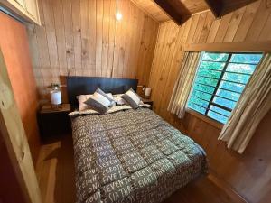 una camera da letto con un letto in una stanza di legno di Casa en el centro de Licanray a Licán Ray