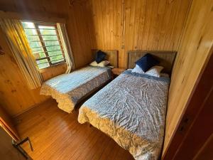 2 letti in una camera in legno con finestra di Casa en el centro de Licanray a Licán Ray