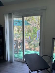 een glazen schuifdeur met een tafel en een paraplu bij Dos alcobas, entrada independiente in Kissimmee