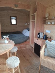 een slaapkamer met een bed, een tafel en stoelen bij Roulotte & Respire in Foussemagne