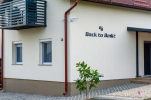 een wit gebouw met een bord waarop staat: terug naar Brits bij Kuća za odmor Back to Bašić in Mandičevac