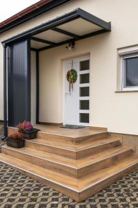 een huis met een houten terras en een witte deur bij Kuća za odmor Back to Bašić in Mandičevac