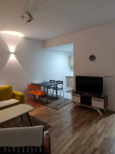 een woonkamer met een tv en een tafel met stoelen bij Borjan Apartment Mavrovo in Mavrovo +2 foto's