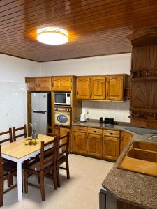a kitchen with wooden cabinets and a wooden table with a tableablish at Casa estrelicia II in Relógio do Poiso