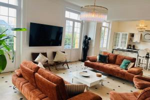 een woonkamer met bruine banken en een televisie bij Hôtel Particulier - 5 minutes de Reims in Reims