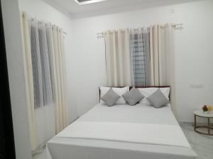 a white bedroom with a bed with four pillows at EVA Residency in Kallar