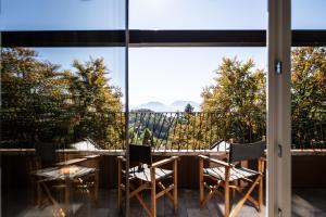 uitzicht vanaf het balkon van een huis met een tafel en stoelen bij Alp Wellness Sport Hotel Panorama in Fai della Paganella