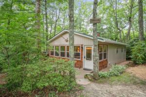 ein kleines weißes Haus im Wald mit Bäumen in der Unterkunft Cozy Pisgah Cabin w Fire Pit in Newland