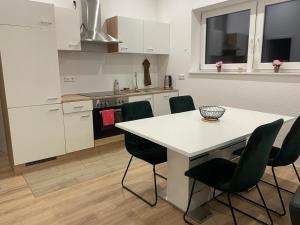 a kitchen with a white table and green chairs at RadlerOase am Donauradweg in Heufelden