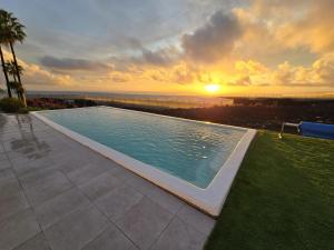 ein Swimmingpool mit einem Sonnenuntergang im Hintergrund in der Unterkunft Villa Las Norias in Tazacorte