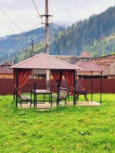 a picnic area with two benches and a roof at Садиба у "Степана" in Synevyrsʼka Polyana