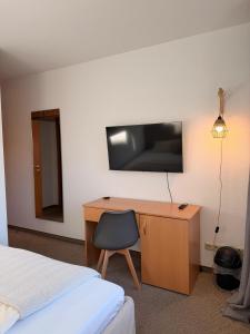 een slaapkamer met een bureau en een tv aan de muur bij Aparthotel Zur Linde - by Willms & Schömer eG in Euskirchen