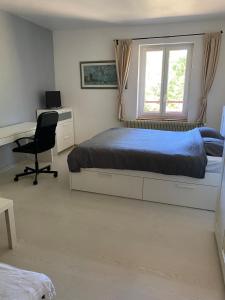 a bedroom with a bed and a desk and a window at La colonie in La Perrena