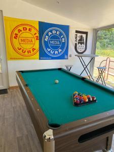 a pool table in a room with signs on the wall at La colonie in La Perrena