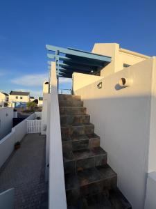 a staircase on the side of a building with a blue sky at Codrock Cottage in Langebaan