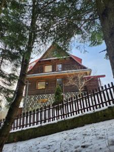 a wooden house with a fence in the snow at Uroczysko pod Babią Górą in Zawoja