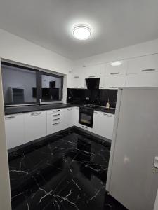 a kitchen with white cabinets and black marble floor at Luxury Private Villa in Tunari +6 photos