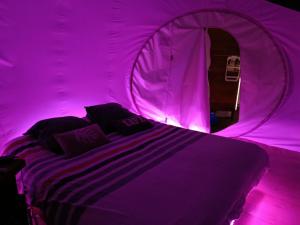 a purple room with a bed in a tent at Les Bulles du Coq de Champagne in Dormans