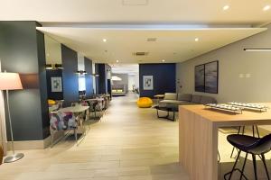 - un hall doté d'un espace d'attente avec des tables et des chaises dans l'établissement Stay Inn Santos Sua acomodação com cara de Hotel, à Santos