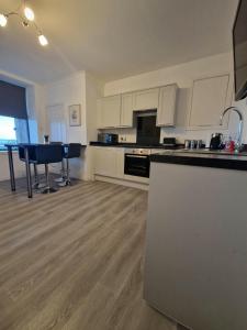 eine große Küche mit weißen Schränken und einem Tisch in der Unterkunft Rook View, Modern Coastal Retreat with Free Parking in Buckie