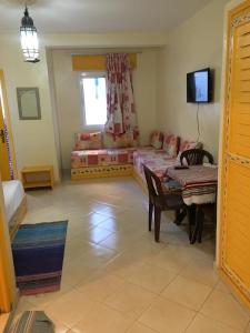 a room with two beds and a table and a tv at Dar Bouanani in Asilah