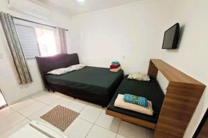 een kleine kamer met een bed en een tv bij Pousada Casa da Fernanda, Suíte Sun in Praia Grande
