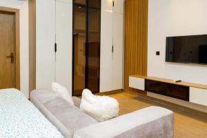 a living room with a white couch and a tv at Studio Room by Elegushi beach resort in Mama