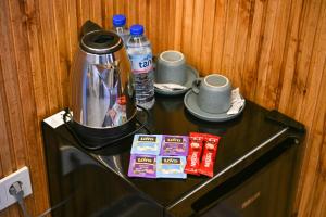 a counter with a coffee pot and cups and water at DejaVu Hotel in Prizren