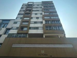 een hoog gebouw met een bord ervoor bij Apartamento no centro de Torres Rs in Torres