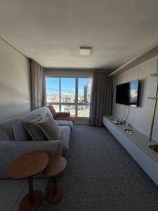 een woonkamer met een bank en een tv bij Apartamento no centro de Torres Rs in Torres