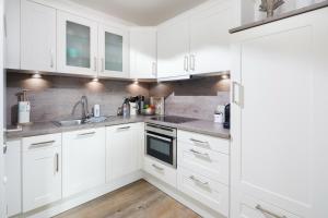 eine weiße Küche mit weißen Schränken und einer Spüle in der Unterkunft Strandperle Ney in Norderney + 6 Fotos