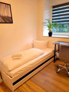 Bett in einem Zimmer mit einem Schreibtisch und einem Fenster in der Unterkunft Entspannen am Großen Goitzschesee in Holzweißig