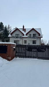 a fence in front of a house in the snow at Świat Jezior in Mikołajki
