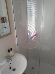 een witte badkamer met een wastafel en een douche bij 2-bed Hide-away Caravan at Ashbourne Heights in Fenny Bentley