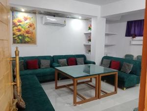 a living room with a green couch and a table at Malti Guest House in Kullu Manali