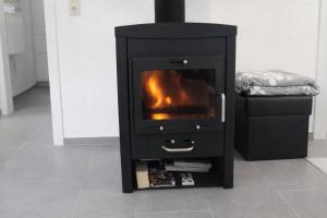 a black stove with a fireplace in a room at Familien- & haustierfreundliche Ferienwohnung mit Garten nahe Ostsee in Schashagen