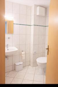 een witte badkamer met een toilet en een wastafel bij Hotel & Restaurant Hasa in Gernrode - Harz