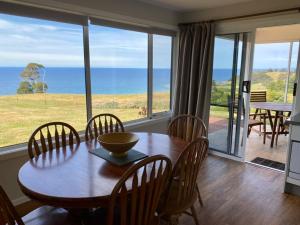 a dining room with a table and chairs and the ocean at Penguin Seaside Farm in Penguin