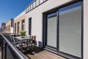 ein Balkon mit Tisch und Stühlen und einem Fenster in der Unterkunft Robbenloft in Norderney